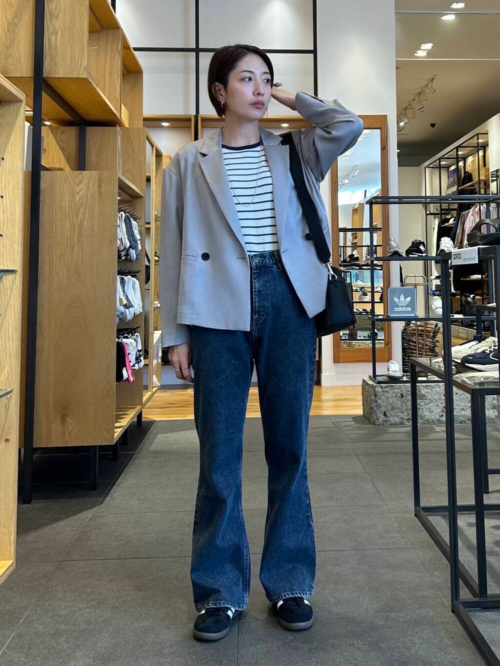 ブルー系のデニムパンツ、ブラック系のショルダーバッグ、グレー系のその他アウターを着用したレディースの春コーディネートの2枚目の写真