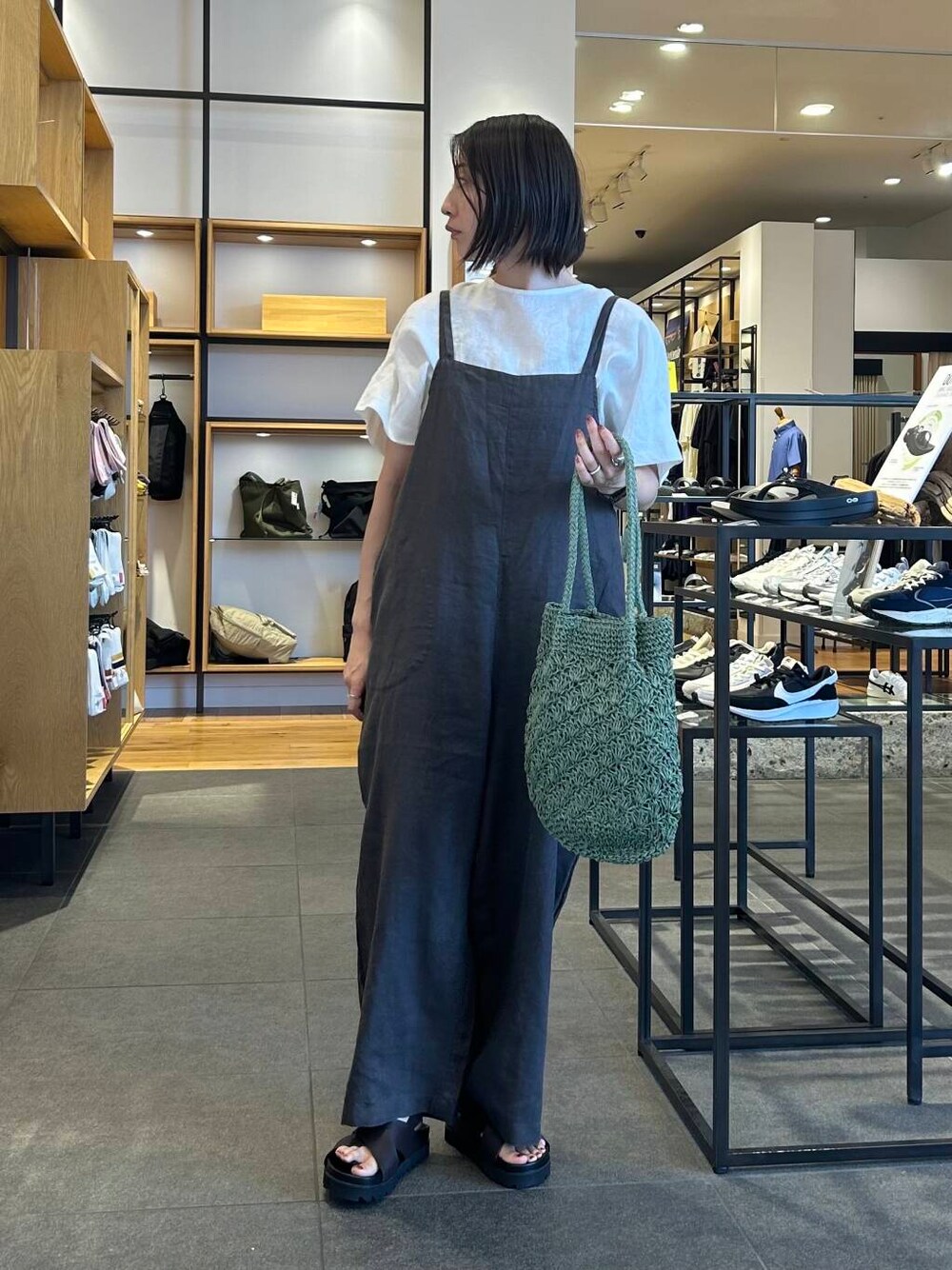 グリーン系のトートバッグ、グレー系のサロペット/オーバーオール、ブラウン系のサンダルを着用したレディースの夏コーディネートの3枚目の写真