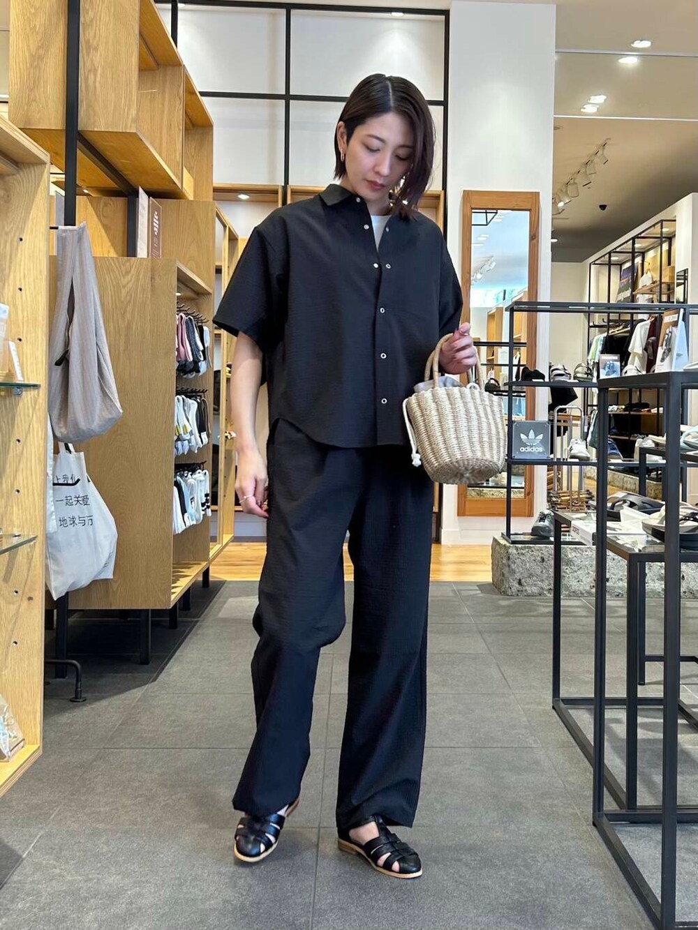 ブラック系のサンダル、グレー系のハンドバッグ、ホワイト系のTシャツ/カットソーを着用したレディースの夏コーディネートの2枚目の写真