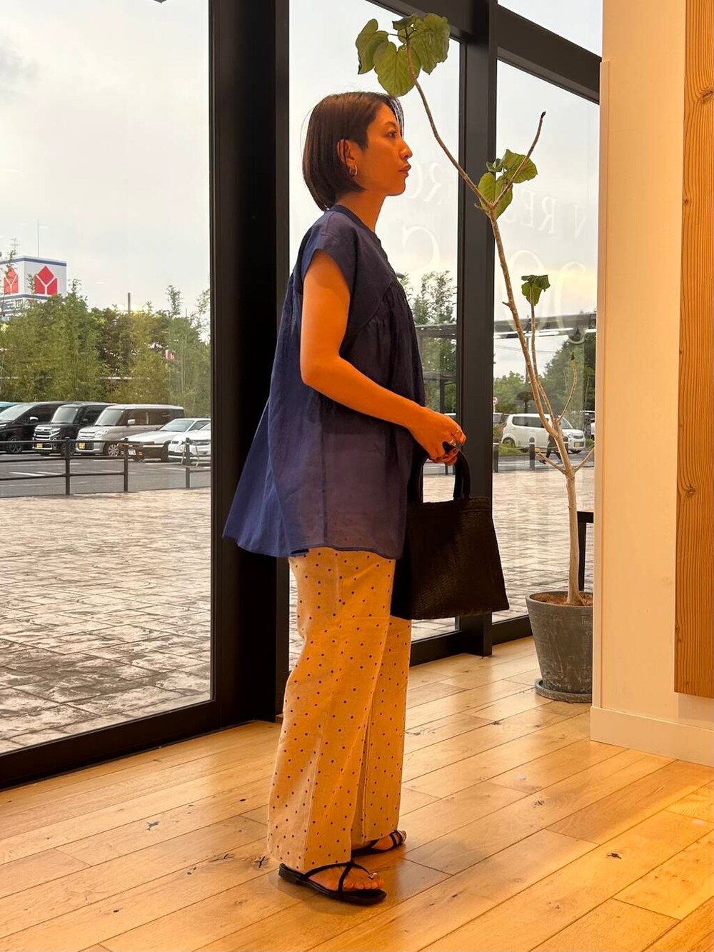 ブラック系のハンドバッグ、ベージュ系のその他パンツ、ブルー系のシャツ/ブラウスを着用したレディースの夏コーディネートの4枚目の写真