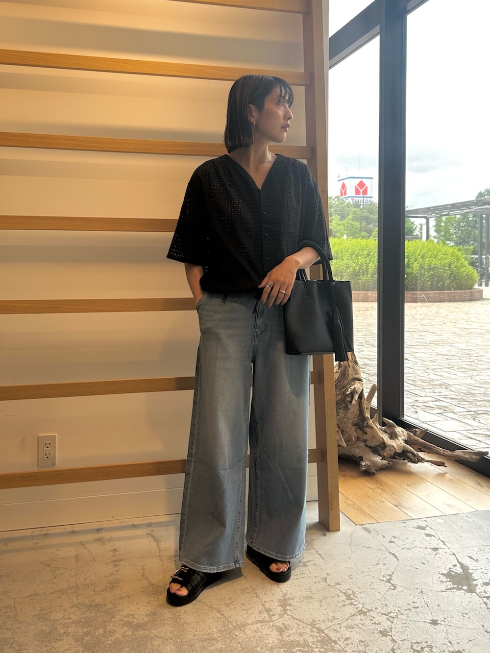 ブルー系のデニムパンツ、ブラック系のトートバッグ、ブラック系のサンダルを着用したレディースの夏コーディネートの3枚目の写真