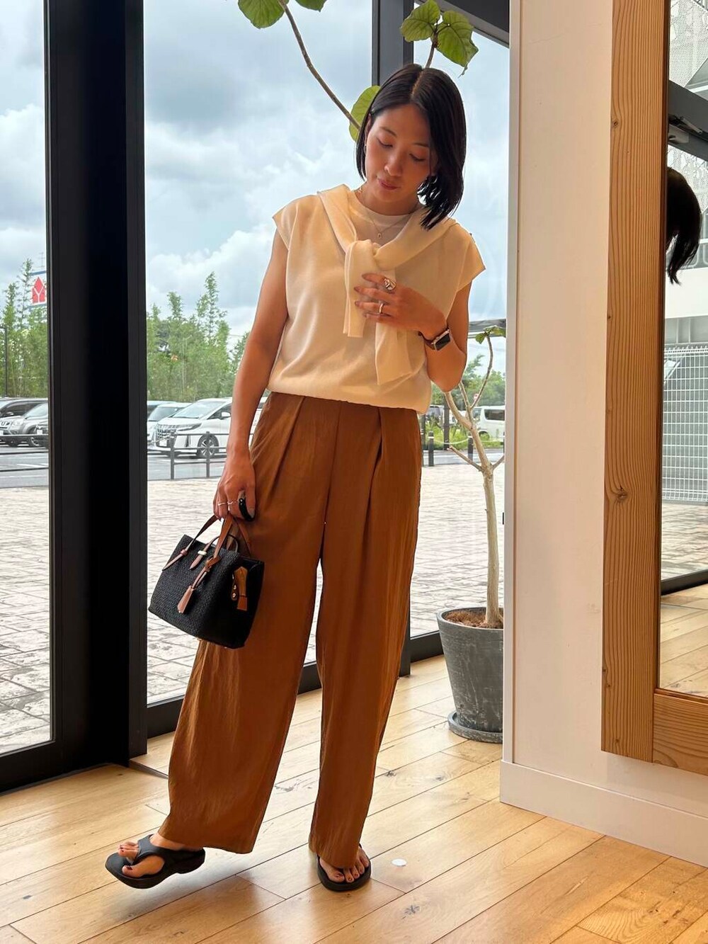 ブラック系のサンダル、ブラック系のトートバッグ、ホワイト系のニット/セーターを着用したレディースの夏コーディネートの5枚目の写真