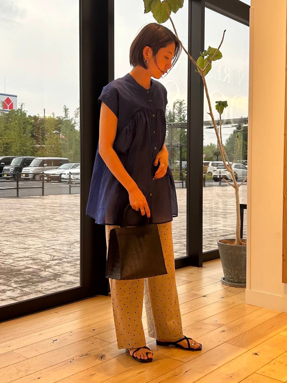 ブラック系のハンドバッグ、ベージュ系のその他パンツ、ブルー系のシャツ/ブラウスを着用したレディースの夏コーディネートの3枚目の写真