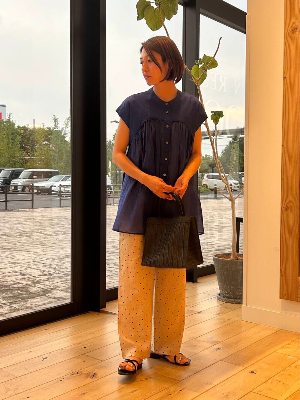 ブラック系のハンドバッグ、ベージュ系のその他パンツ、ブルー系のシャツ/ブラウスを着用したレディースの夏コーディネートの2枚目の写真