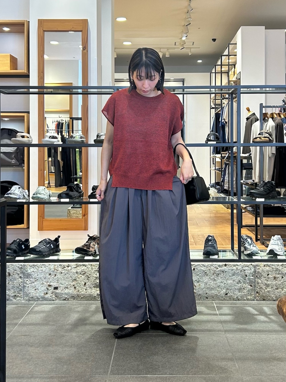レッド系のその他トップス、グレー系のその他パンツ、ブラック系のハンドバッグを着用したレディースの夏コーディネートの2枚目の写真