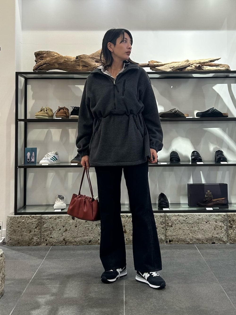 レッド系のショルダーバッグ、ブラック系のデニムパンツ、ブラック系のスニーカーを着用したレディースの秋コーディネートの2枚目の写真