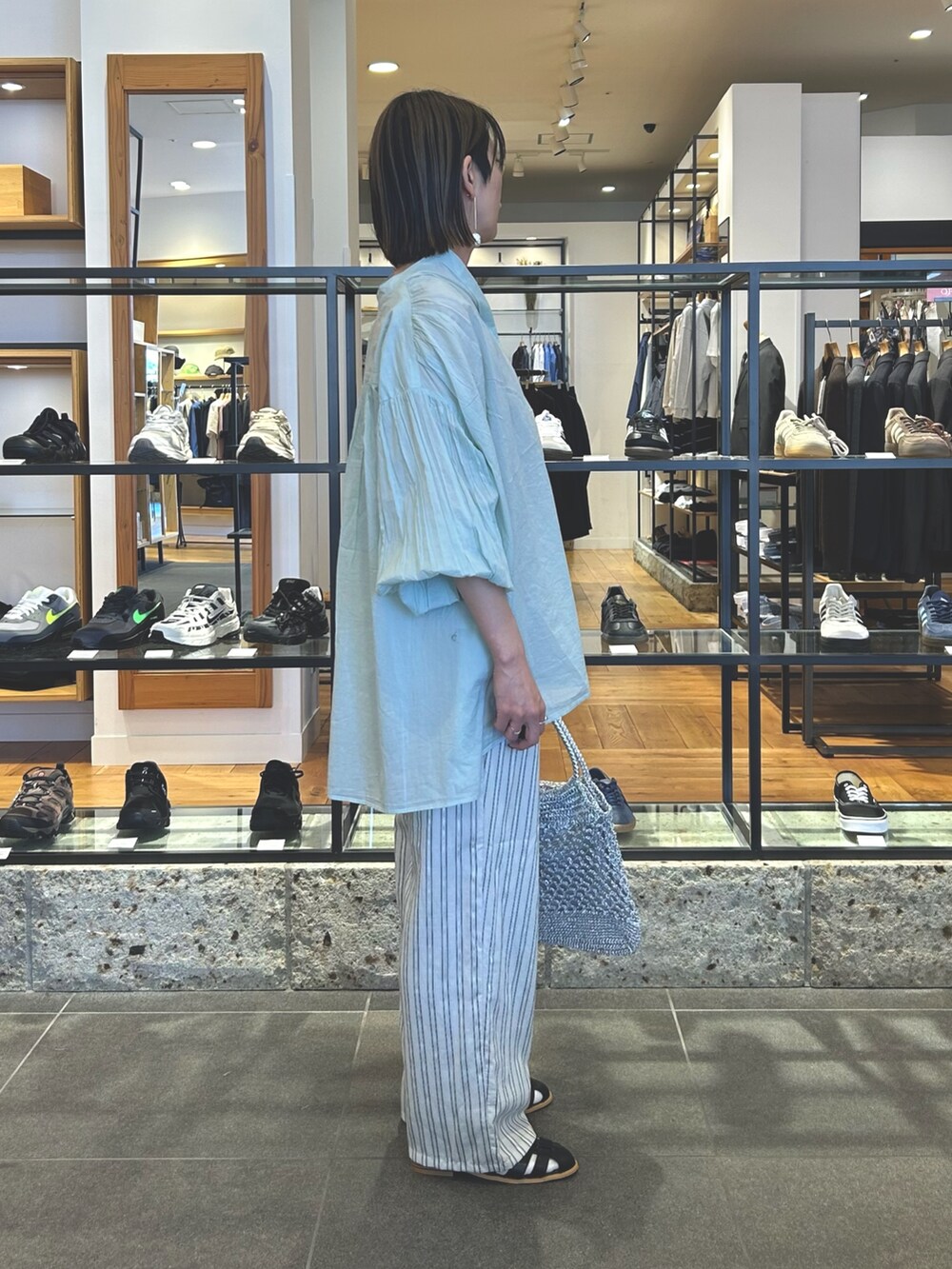 グレー系のその他パンツ、シルバー系のトートバッグ、ブラック系のサンダルを着用したレディースの春コーディネートの3枚目の写真