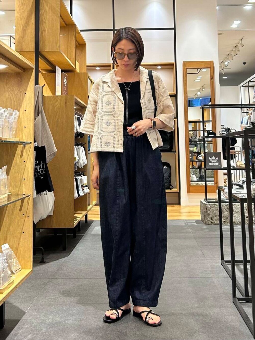 ブルー系のデニムパンツ、ブラック系のバックパック/リュック、ブラック系のタンクトップを着用したレディースの夏コーディネートの5枚目の写真