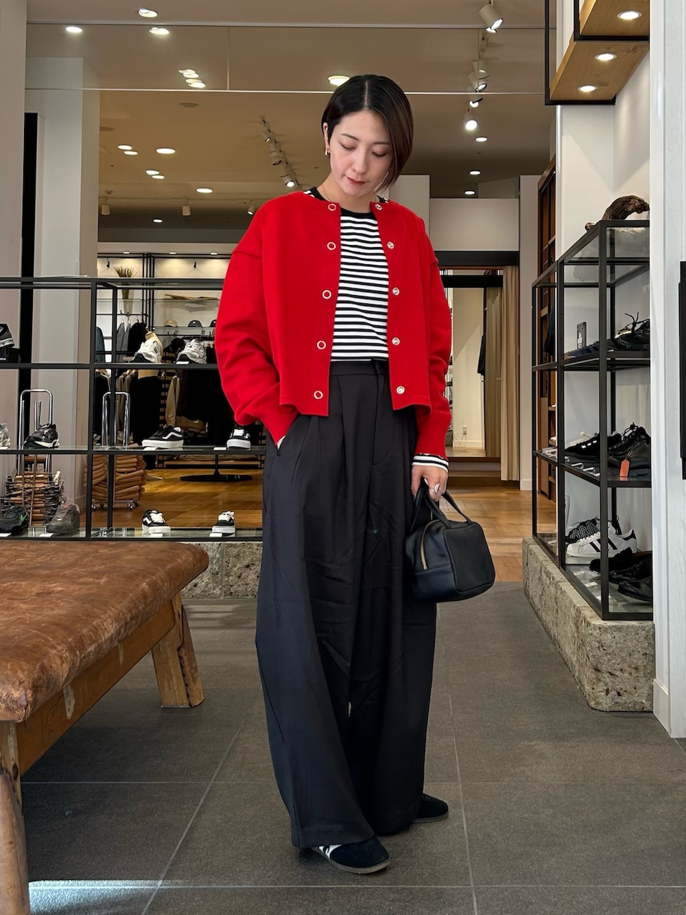 ブラック系のスニーカー、ブラック系のボストンバッグ、レッド系のカーディガン/ボレロを着用したレディースの秋コーディネートの4枚目の写真