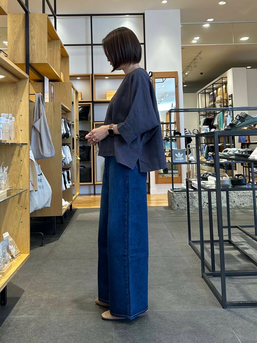 ブルー系のデニムパンツ、オレンジ系のトートバッグ、ベージュ系のバレエシューズを着用したレディースの夏コーディネートの4枚目の写真