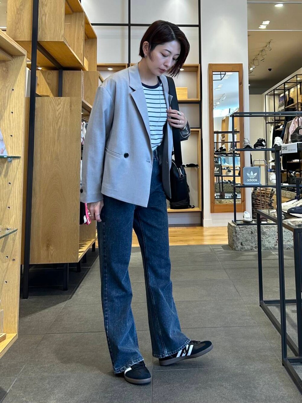 ブルー系のデニムパンツ、ブラック系のショルダーバッグ、グレー系のその他アウターを着用したレディースの春コーディネートの3枚目の写真