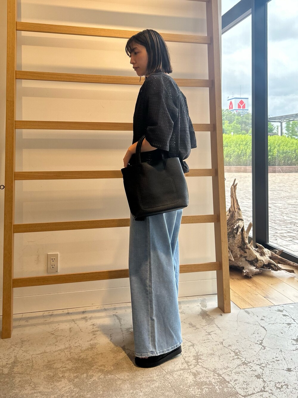 ブルー系のデニムパンツ、ブラック系のトートバッグ、ブラック系のサンダルを着用したレディースの夏コーディネートの4枚目の写真