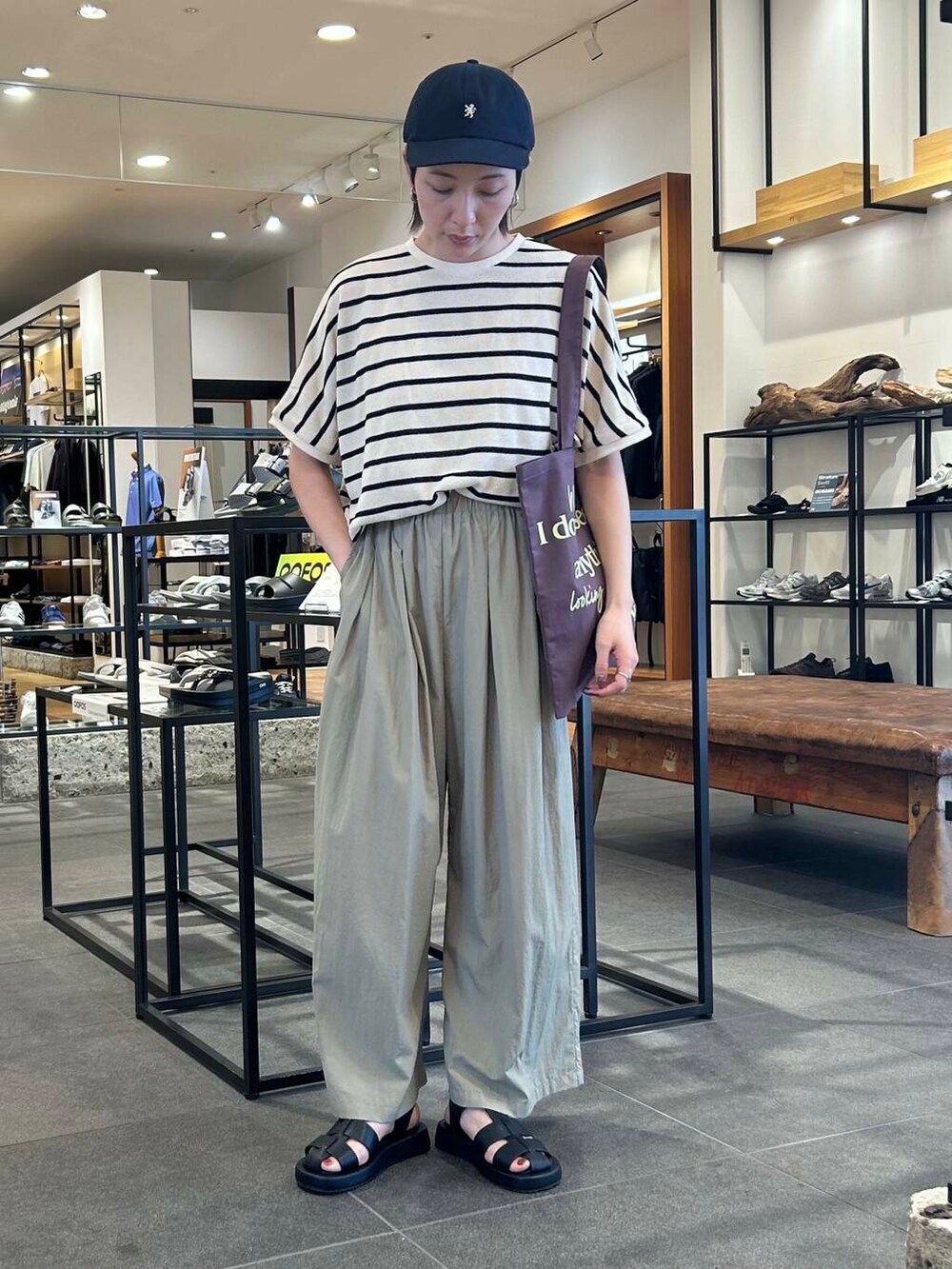 ブラウン系のトートバッグ、ベージュ系のその他パンツ、ブラック系のサンダルを着用したレディースの夏コーディネートの2枚目の写真