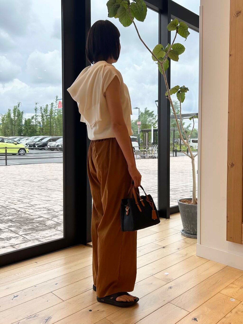 ブラック系のサンダル、ブラック系のトートバッグ、ホワイト系のニット/セーターを着用したレディースの夏コーディネートの3枚目の写真