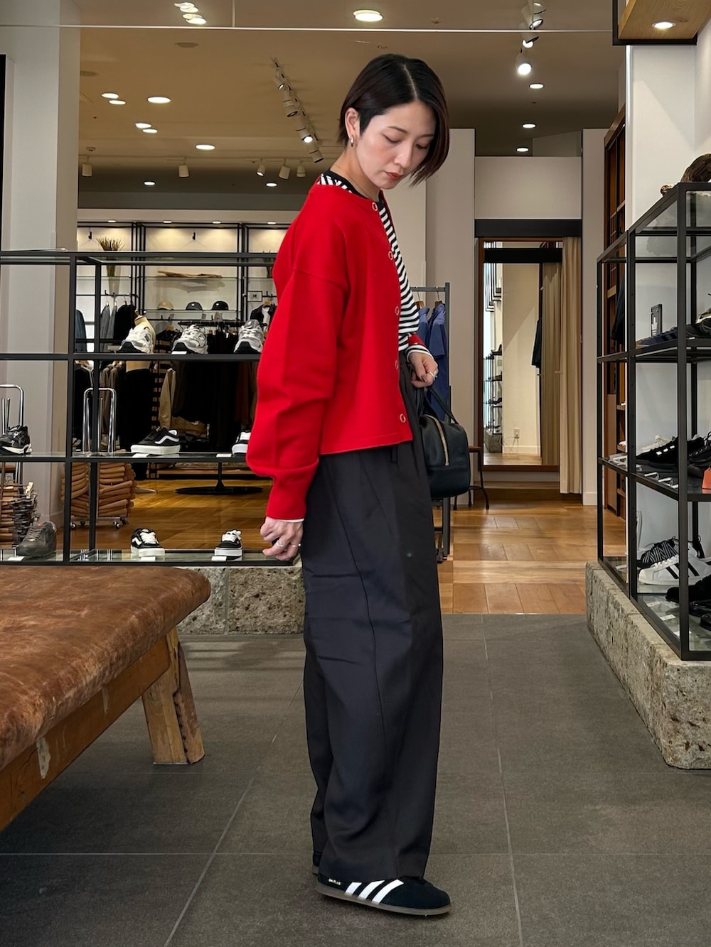 ブラック系のスニーカー、ブラック系のボストンバッグ、レッド系のカーディガン/ボレロを着用したレディースの秋コーディネートの5枚目の写真