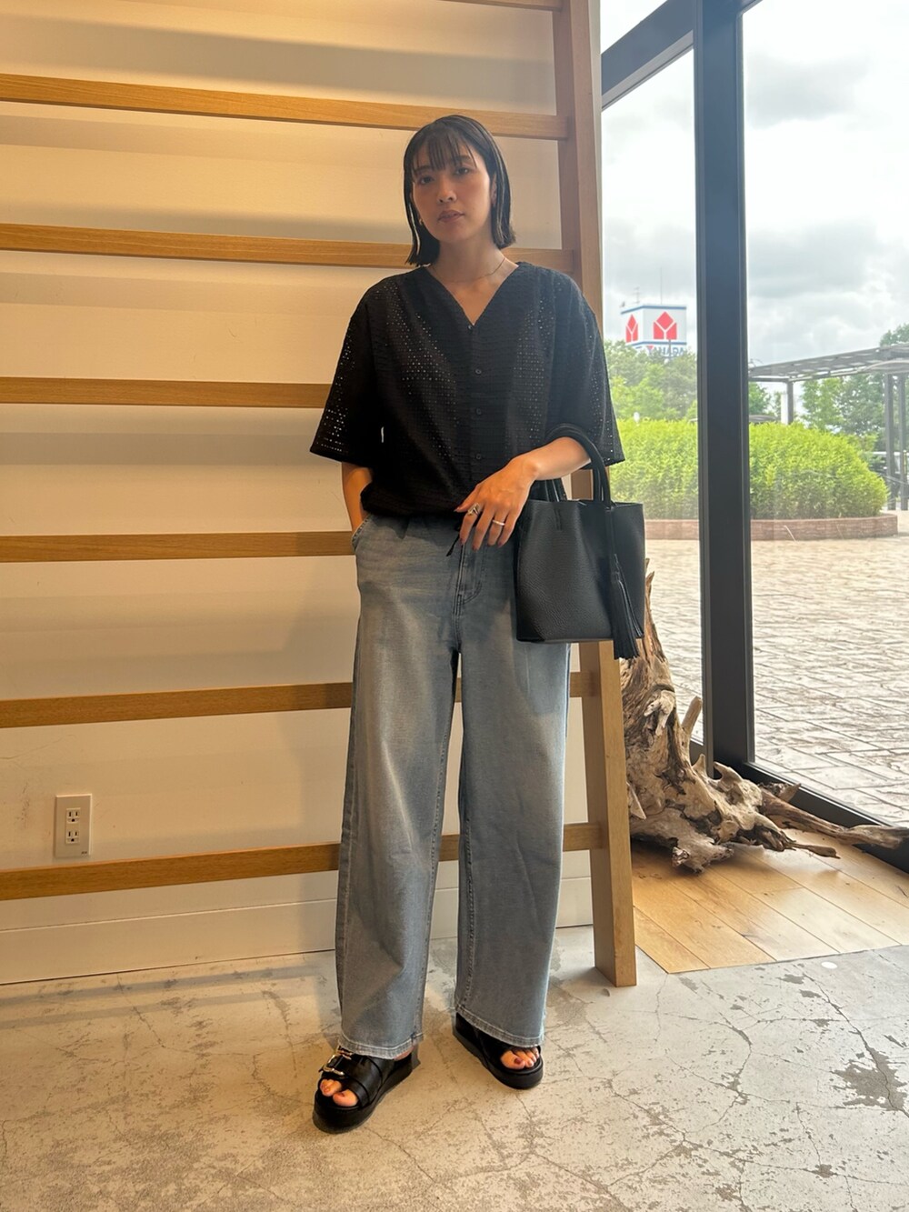 ブルー系のデニムパンツ、ブラック系のトートバッグ、ブラック系のサンダルを着用したレディースの夏コーディネートの2枚目の写真
