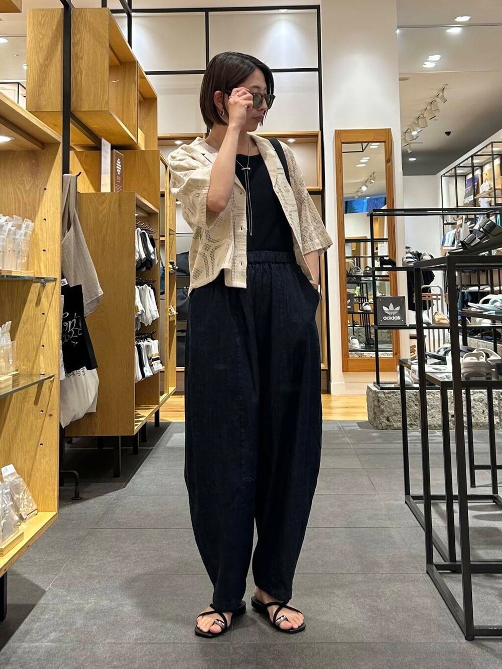 ブルー系のデニムパンツ、ブラック系のバックパック/リュック、ブラック系のタンクトップを着用したレディースの夏コーディネートの4枚目の写真