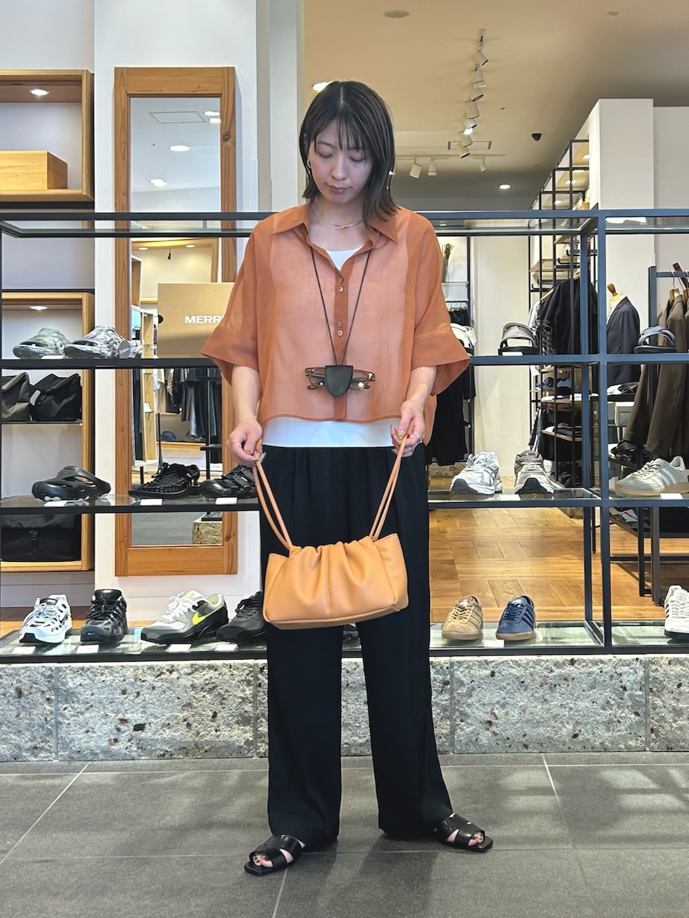 ブラック系のその他パンツ、ブラック系のサンダル、オレンジ系のショルダーバッグを着用したレディースの春コーディネートの2枚目の写真