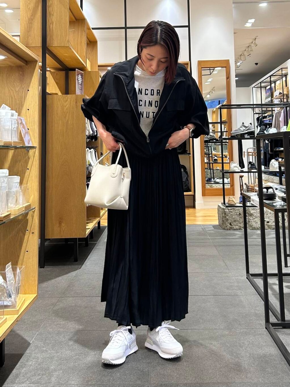 ホワイト系のハンドバッグ、ホワイト系のスニーカー、ブラック系のブルゾンを着用したレディースの春コーディネートの3枚目の写真