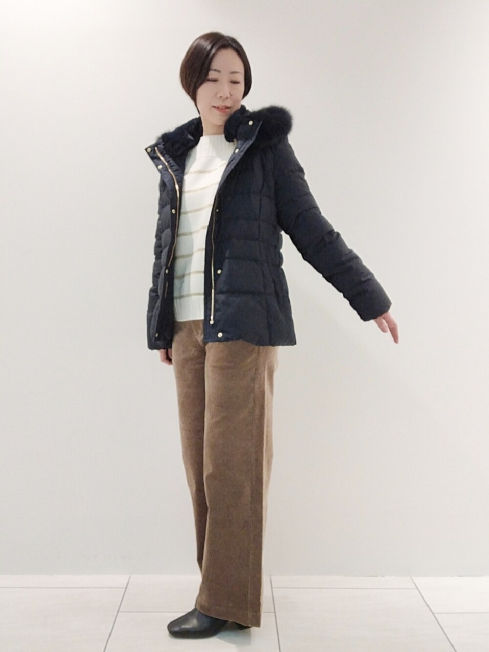 ブルー系のダウンジャケット/コート、ホワイト系のニット/セーター、ベージュ系のその他パンツを着用したレディースの冬コーディネートの3枚目の写真