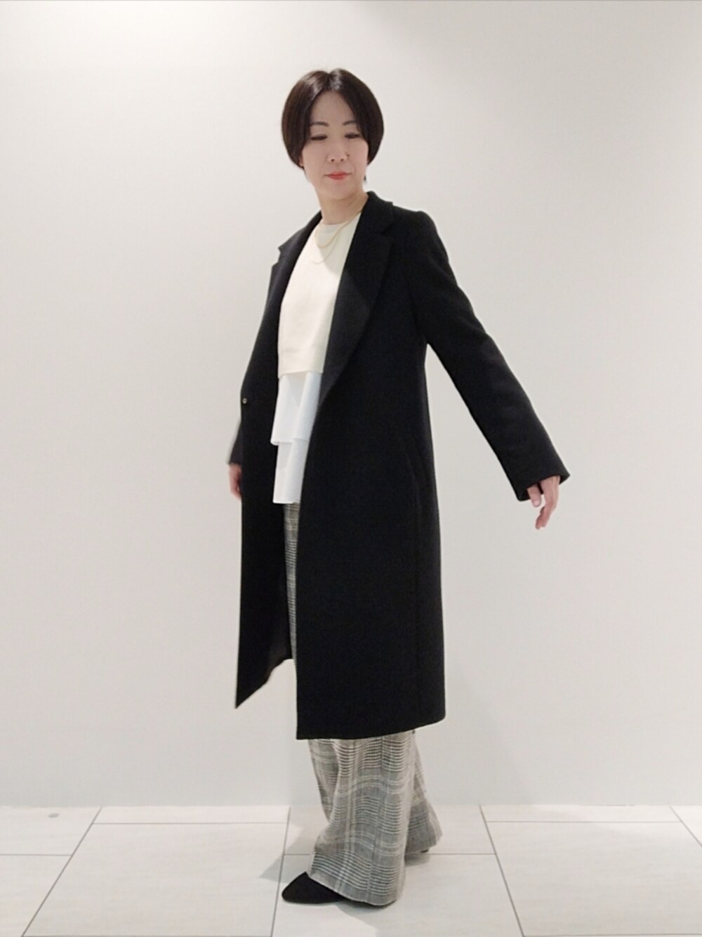 ホワイト系のニット/セーター、ホワイト系のその他パンツ、ブラック系のチェスターコートを着用したレディースの冬コーディネートの3枚目の写真
