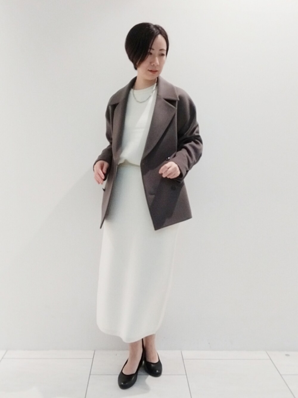 ブラウン系のピーコート、ホワイト系のスカート、ホワイト系のニット/セーターを着用したレディースの秋コーディネートの2枚目の写真