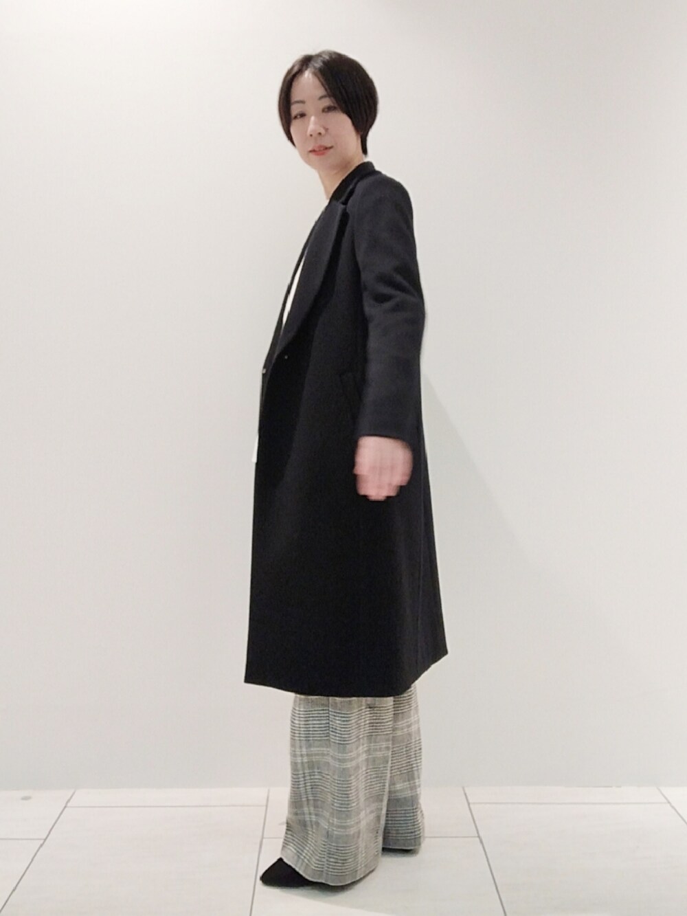 ホワイト系のニット/セーター、ホワイト系のその他パンツ、ブラック系のチェスターコートを着用したレディースの冬コーディネートの4枚目の写真
