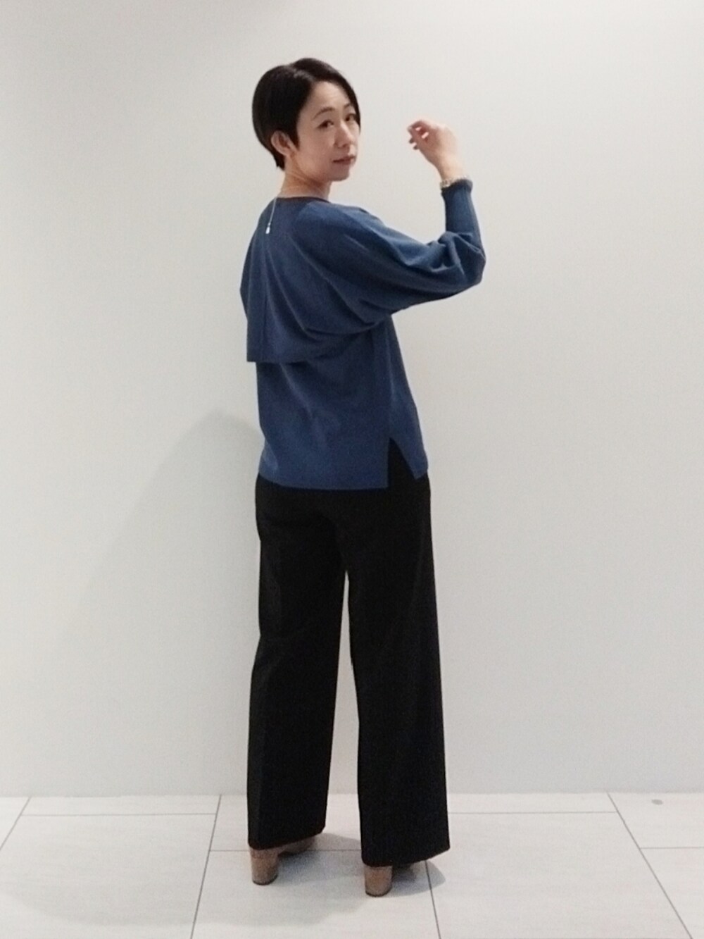 ブルー系のアンサンブル、ブラック系のスーツパンツ、シルバー系のネックレスを着用したレディースの秋コーディネートの5枚目の写真