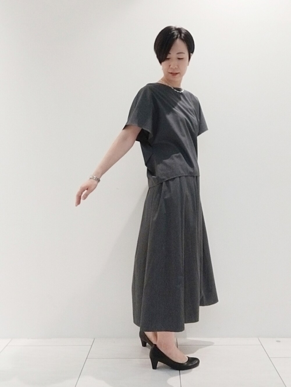 グレー系のシャツ/ブラウス、グレー系のスカート、シルバー系のネックレスを着用したレディースの夏コーディネートの3枚目の写真