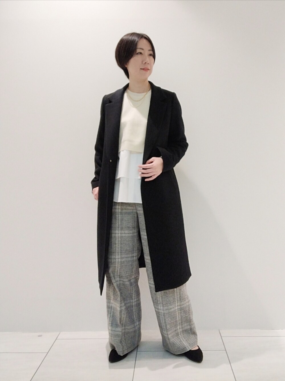 ホワイト系のニット/セーター、ホワイト系のその他パンツ、ブラック系のチェスターコートを着用したレディースの冬コーディネートの2枚目の写真