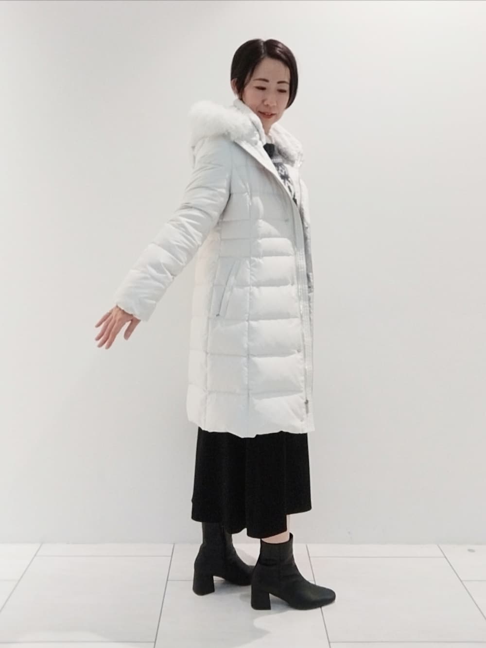 グレー系のニット/セーター、ホワイト系のシャツ/ブラウス、グレー系のダウンジャケット/コートを着用したレディースの冬コーディネートの4枚目の写真