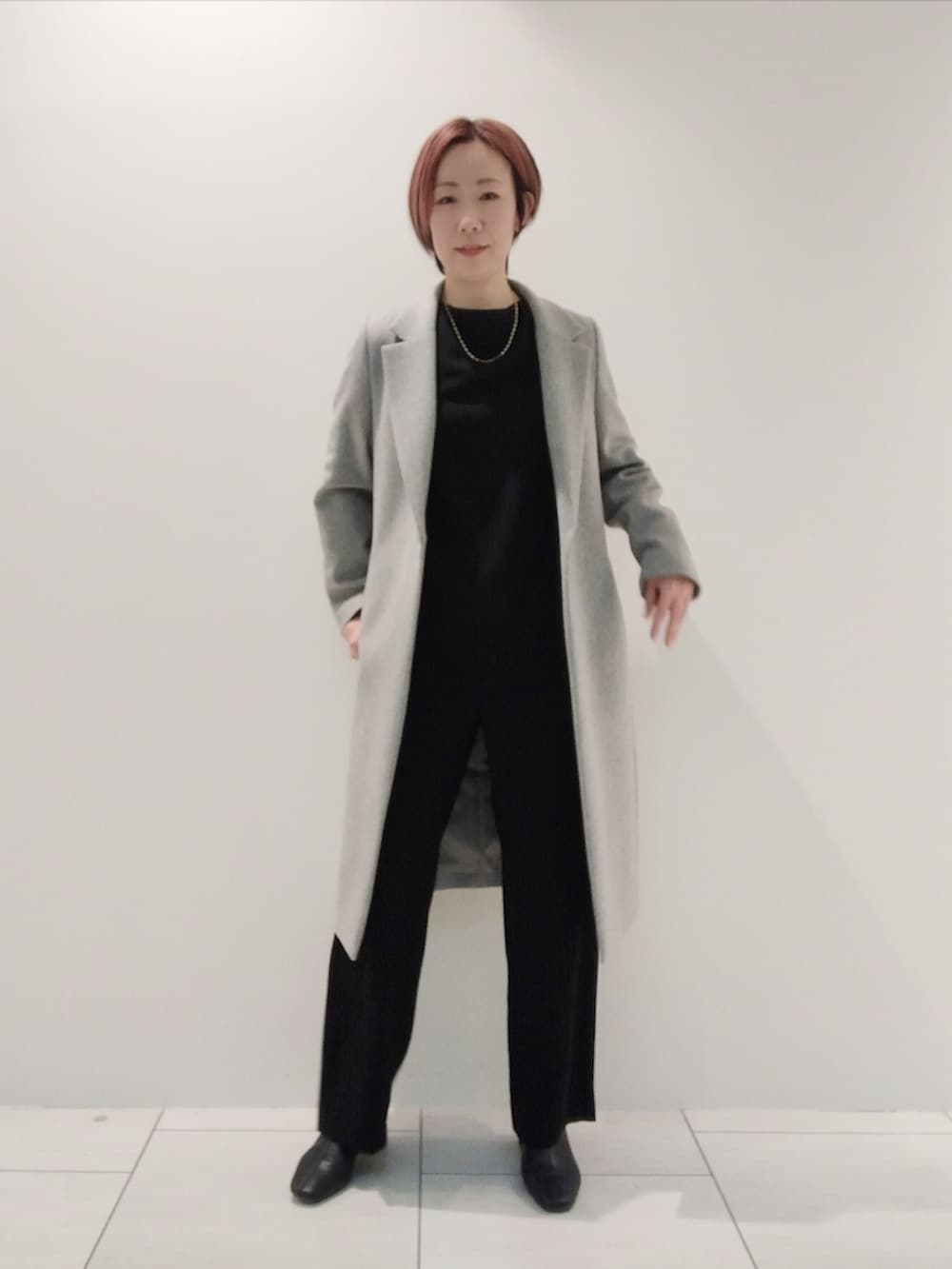 グレー系のチェスターコート、ブラック系のシャツ/ブラウス、ブラック系のスーツパンツを着用したレディースの冬コーディネートの2枚目の写真