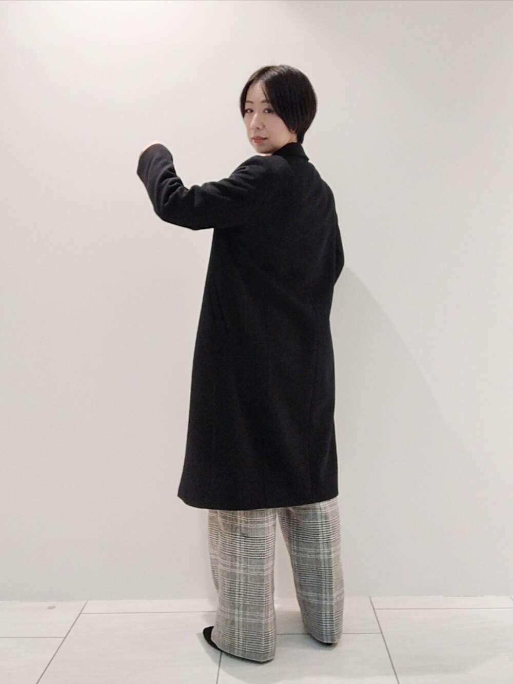 ホワイト系のニット/セーター、ホワイト系のその他パンツ、ブラック系のチェスターコートを着用したレディースの冬コーディネートの5枚目の写真