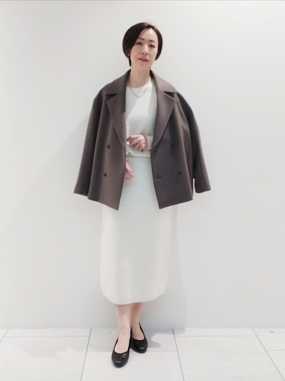 ブラウン系のピーコート、ホワイト系のスカート、ホワイト系のニット/セーターを着用したレディースの秋コーディネートの3枚目の写真