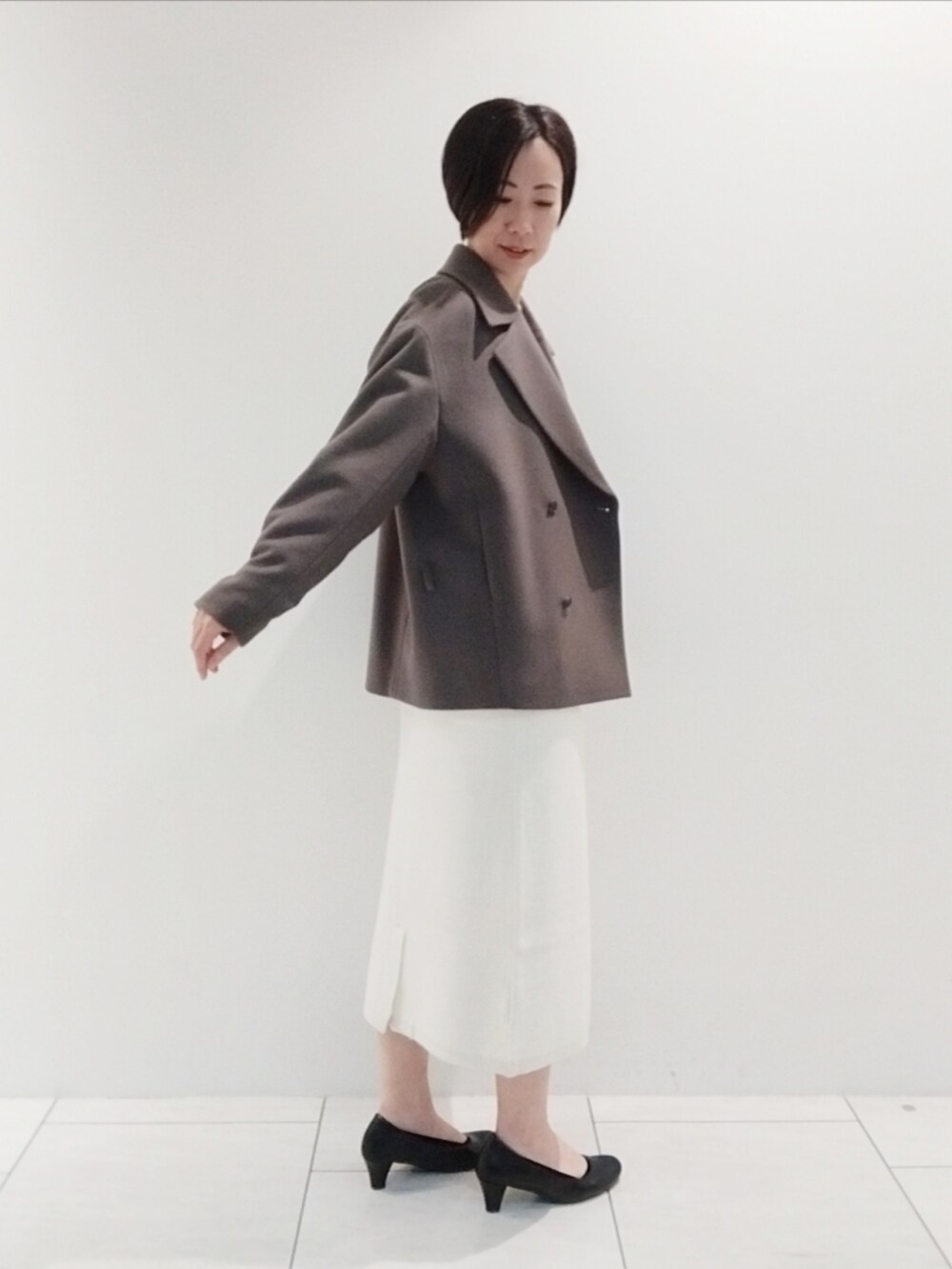 ブラウン系のピーコート、ホワイト系のスカート、ホワイト系のニット/セーターを着用したレディースの秋コーディネートの4枚目の写真