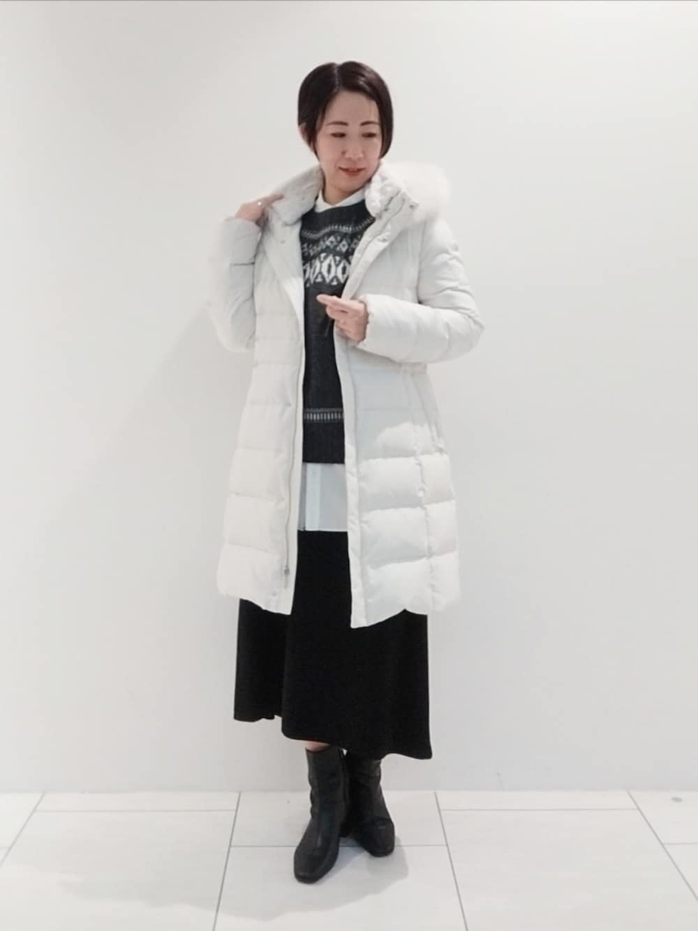 グレー系のニット/セーター、ホワイト系のシャツ/ブラウス、グレー系のダウンジャケット/コートを着用したレディースの冬コーディネートの3枚目の写真