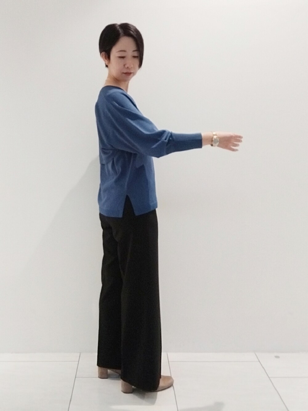 ブルー系のアンサンブル、ブラック系のスーツパンツ、シルバー系のネックレスを着用したレディースの秋コーディネートの4枚目の写真