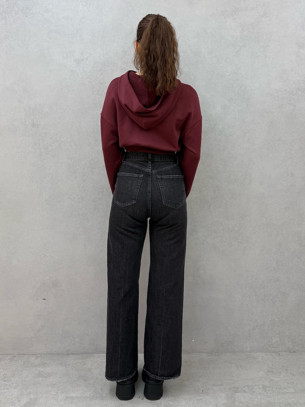 レッド系のパーカー、ブラック系のデニムパンツ、ブラック系のブーツを着用したレディースの秋コーディネートの3枚目の写真