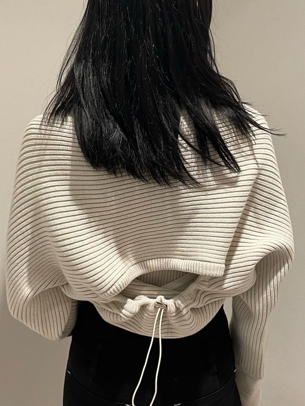 ホワイト系のニット/セーター、ブラック系のデニムパンツ、ブラック系のブーツを着用したレディースの秋コーディネートの6枚目の写真