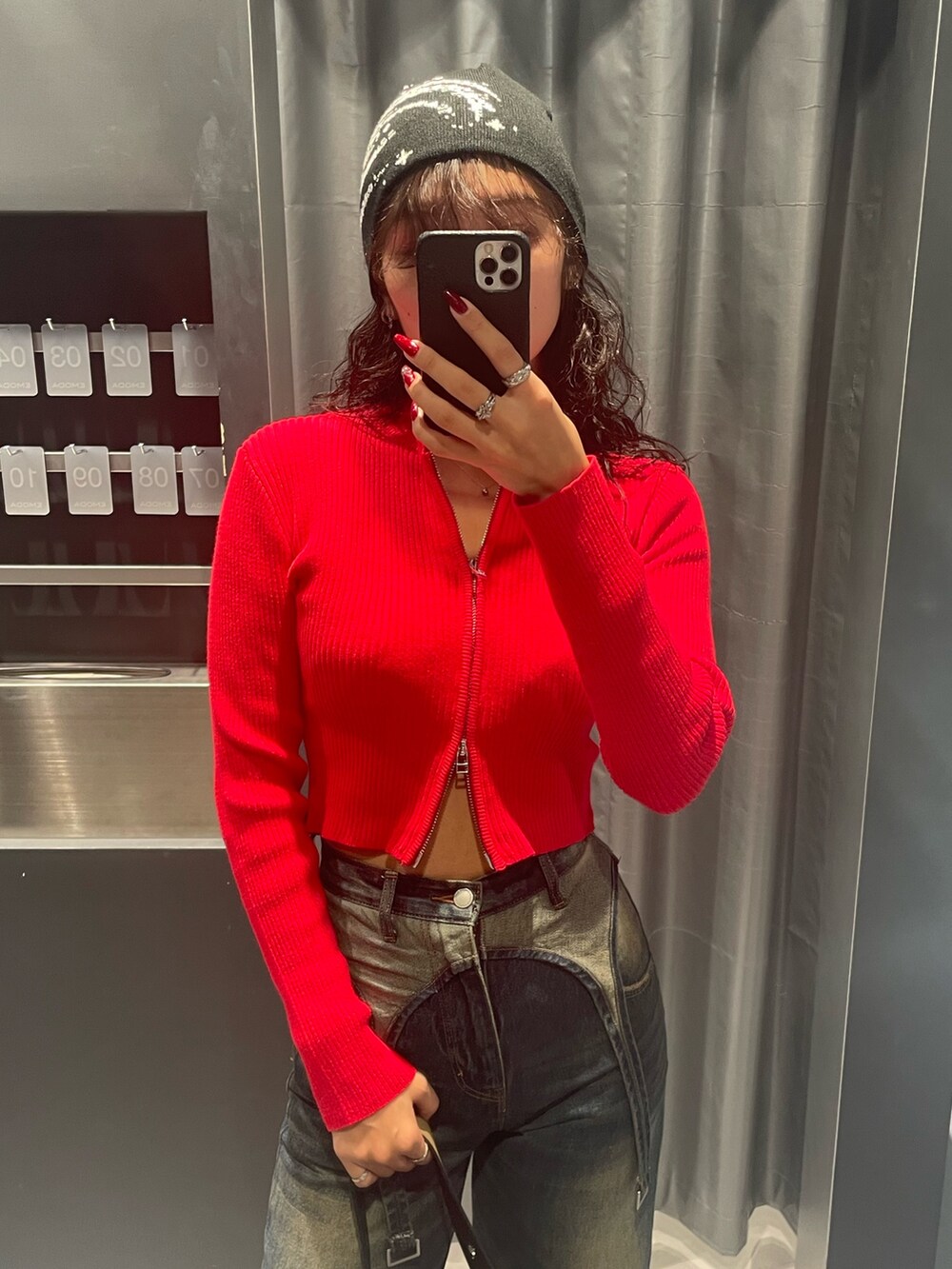 レッド系のニット/セーター、ブルー系のデニムパンツ、ブラック系のハンドバッグを着用したレディースの秋コーディネートの4枚目の写真