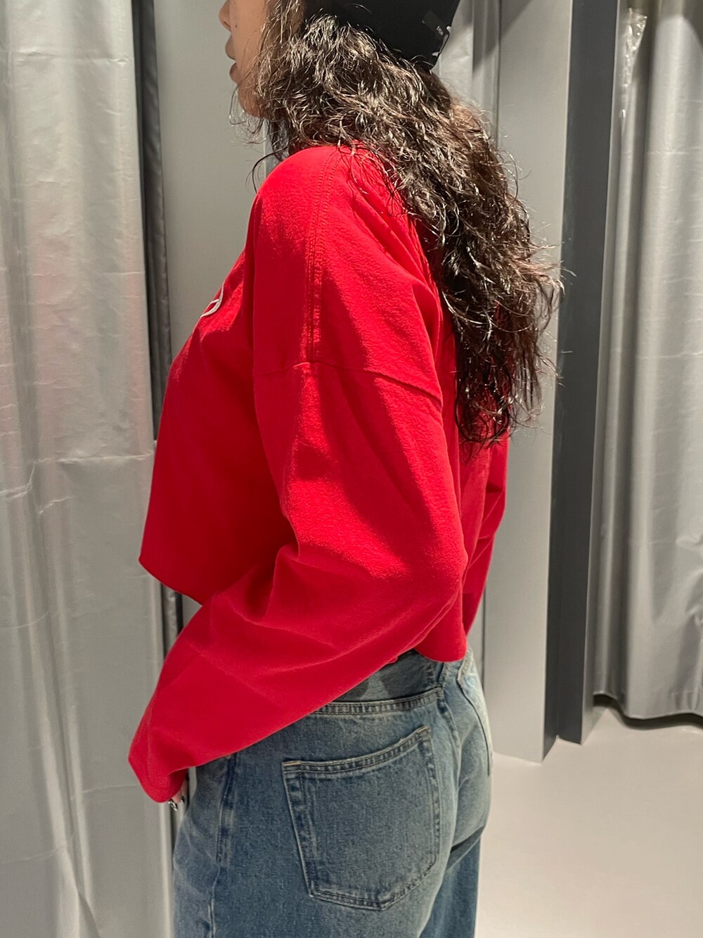 レッド系のTシャツ/カットソー、ブルー系のデニムパンツ、ブラック系のブーツを着用したレディースの秋コーディネートの5枚目の写真