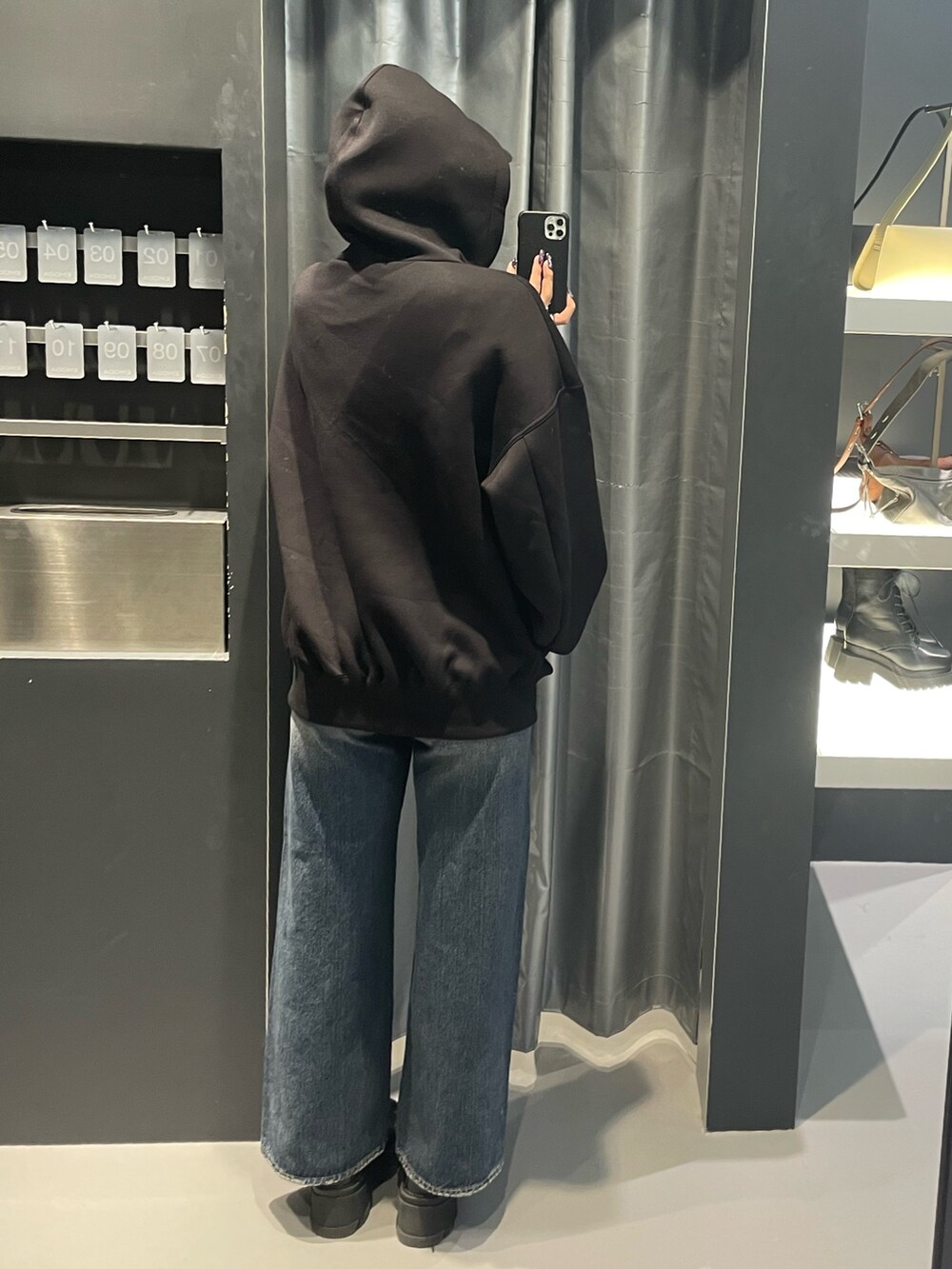 ブラック系のパーカー、ブルー系のデニムパンツ、ブラック系のブーツを着用したレディースの秋コーディネートの3枚目の写真