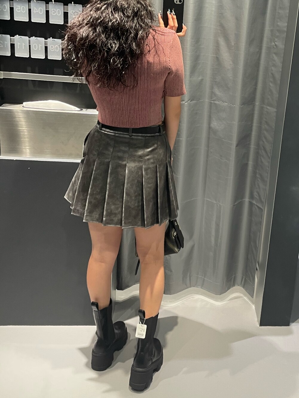 ピンク系のニット/セーター、グレー系のスカート、ブラック系のハンドバッグを着用したレディースの夏コーディネートの3枚目の写真