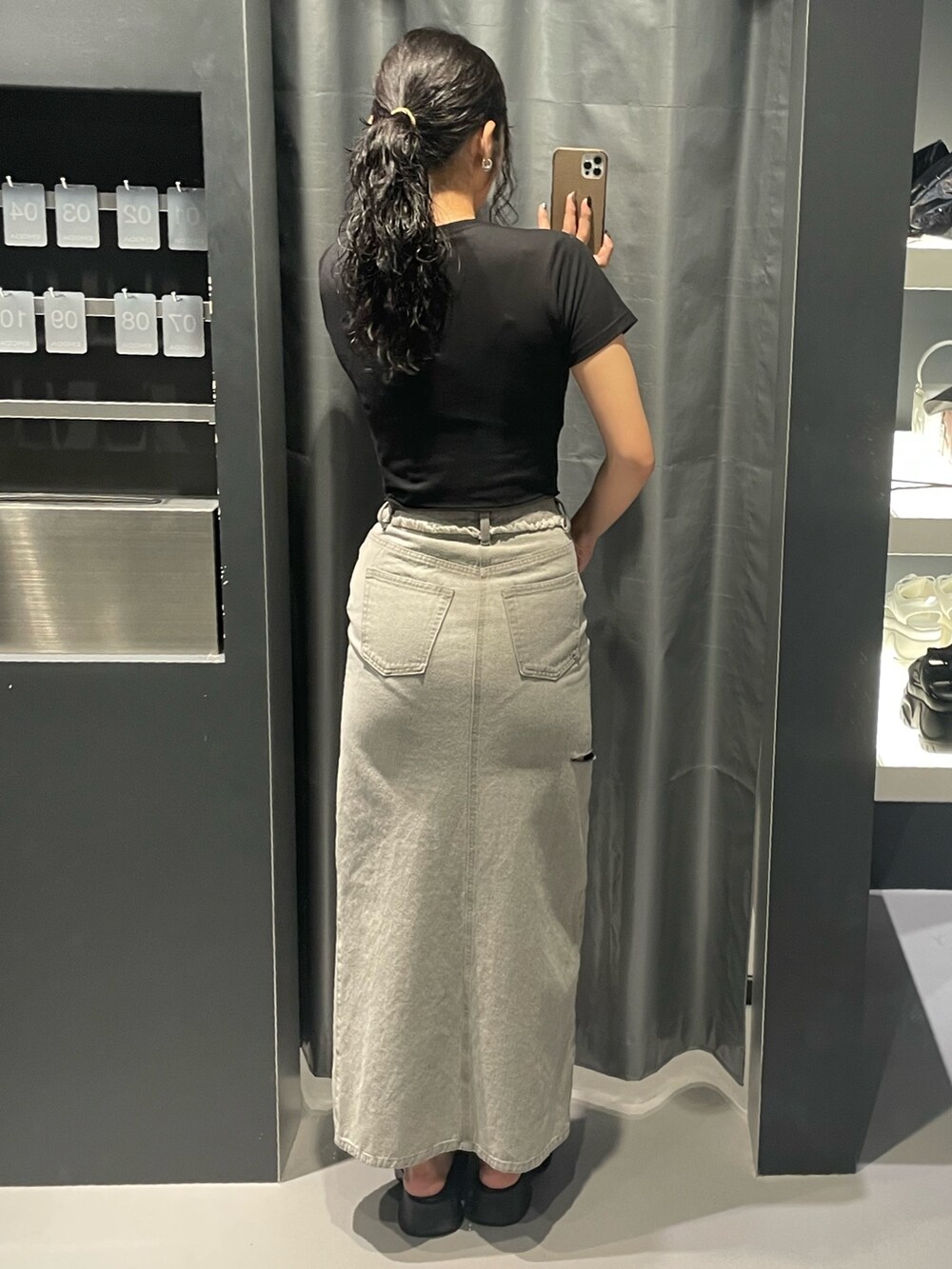 ブラック系のTシャツ/カットソー、グレー系のデニムスカート、ブラック系のサンダルを着用したレディースの夏コーディネートの5枚目の写真