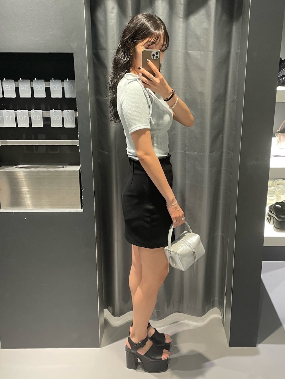 ブルー系のTシャツ/カットソー、ブラック系のスカート、シルバー系のハンドバッグを着用したレディースの夏コーディネートの2枚目の写真