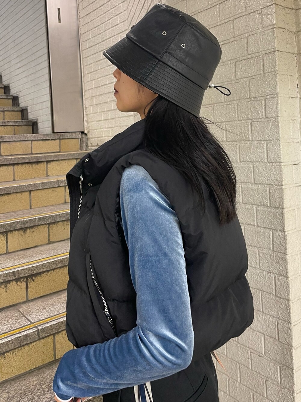 ブラック系のダウンベスト、ブルー系のTシャツ/カットソー、ブラック系のその他パンツを着用したレディースの秋コーディネートの5枚目の写真