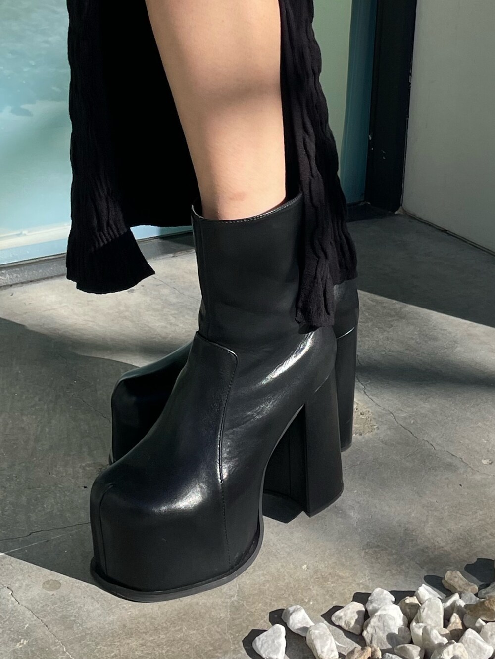 ブラック系のニット/セーター、ブラック系のスカート、ブラック系のブーツを着用したレディースの春コーディネートの8枚目の写真