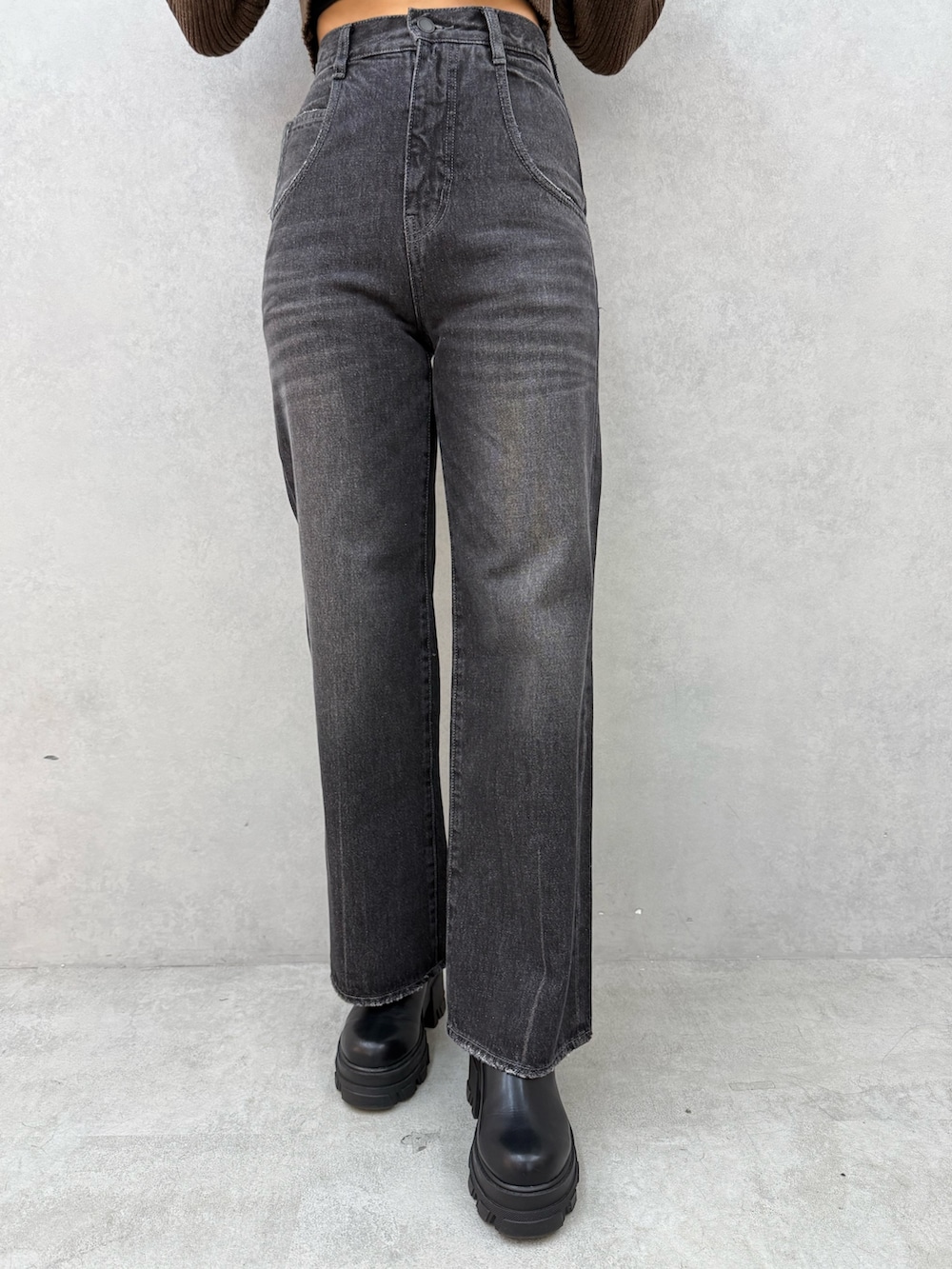 グリーン系のニット/セーター、ブラック系のデニムパンツ、ブラック系のブーツを着用したレディースの秋コーディネートの5枚目の写真