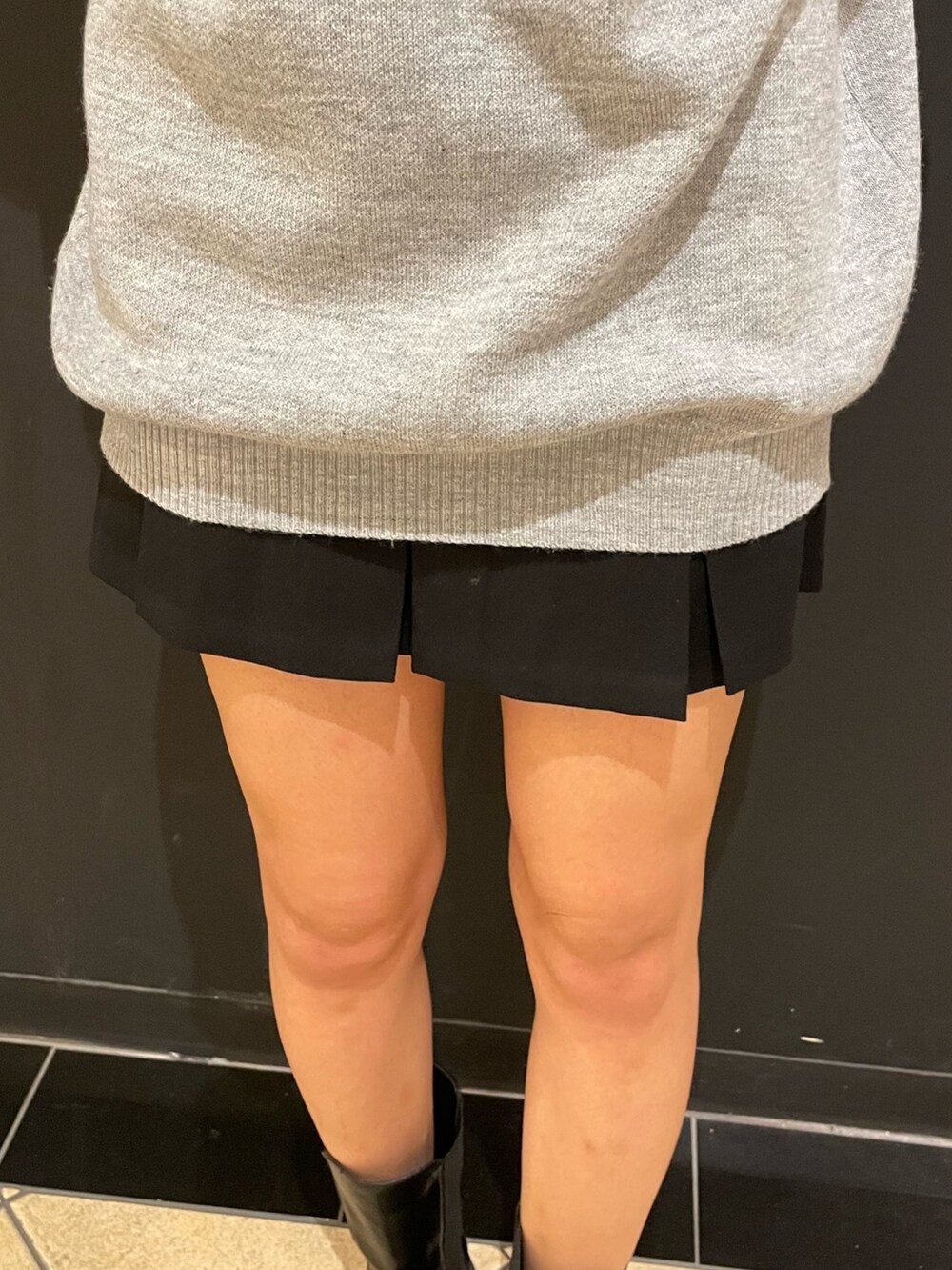 グレー系のワンピース、ブラック系のハンドバッグ、ブラック系のスカートを着用したレディースの秋コーディネートの5枚目の写真