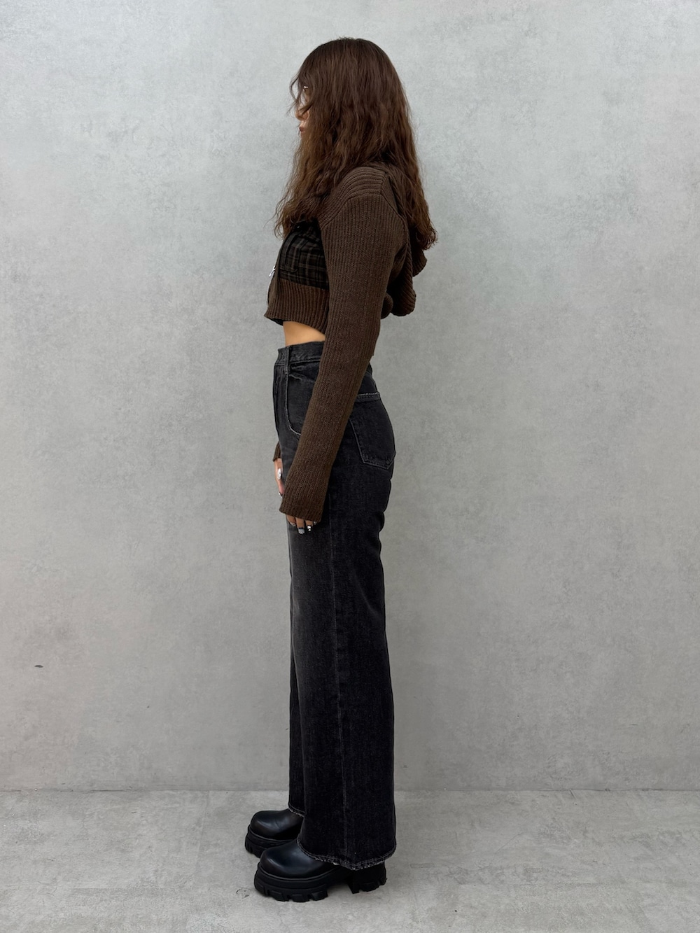 グリーン系のニット/セーター、ブラック系のデニムパンツ、ブラック系のブーツを着用したレディースの秋コーディネートの2枚目の写真